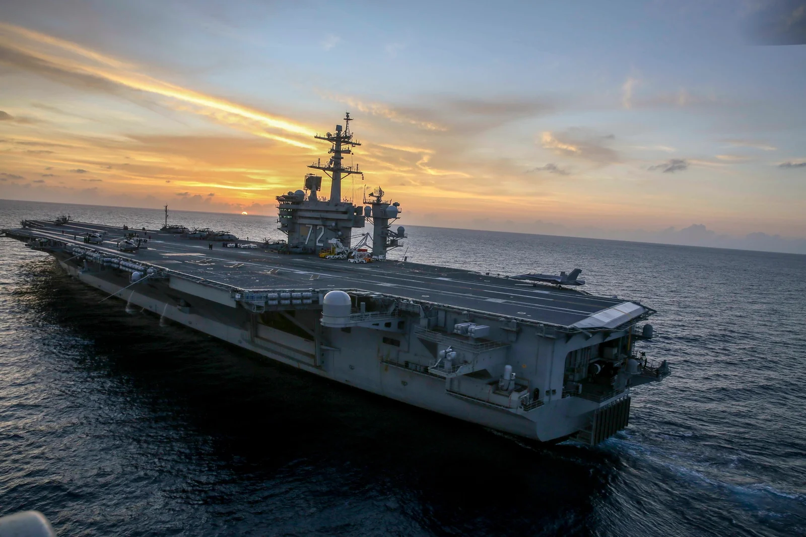 The aircraft carrier USS Abraham Lincoln underway at sunset.