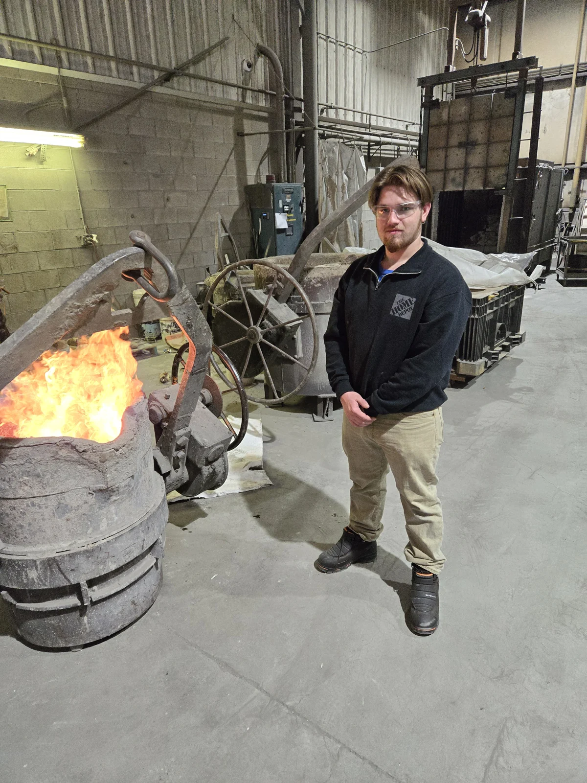 A foundry portrait beside a glowing crucible.